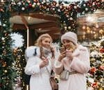 Women enjoying a festive Christmas market in Moscow, embracing winter vibes with warm drinks.